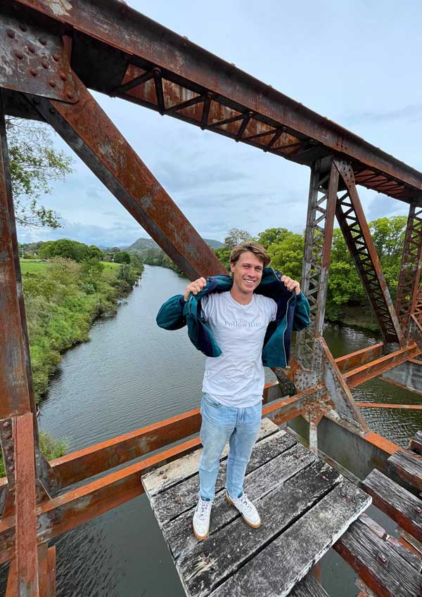 Brainwood Rathbone steht auf Eisenbahnbrücke über einem Fluß.